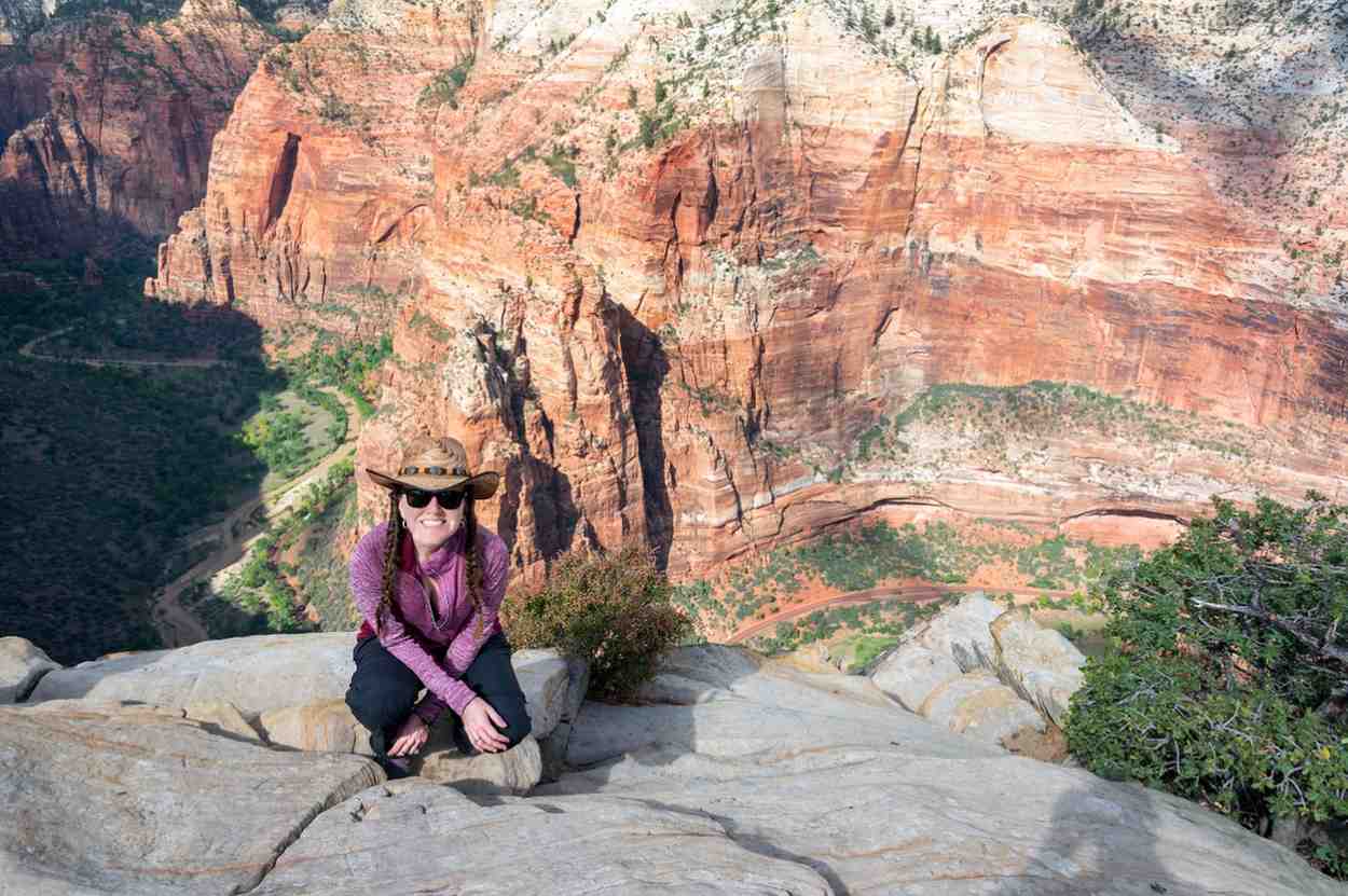 Female hiker posing at scenic overlook with layered red rock canyon